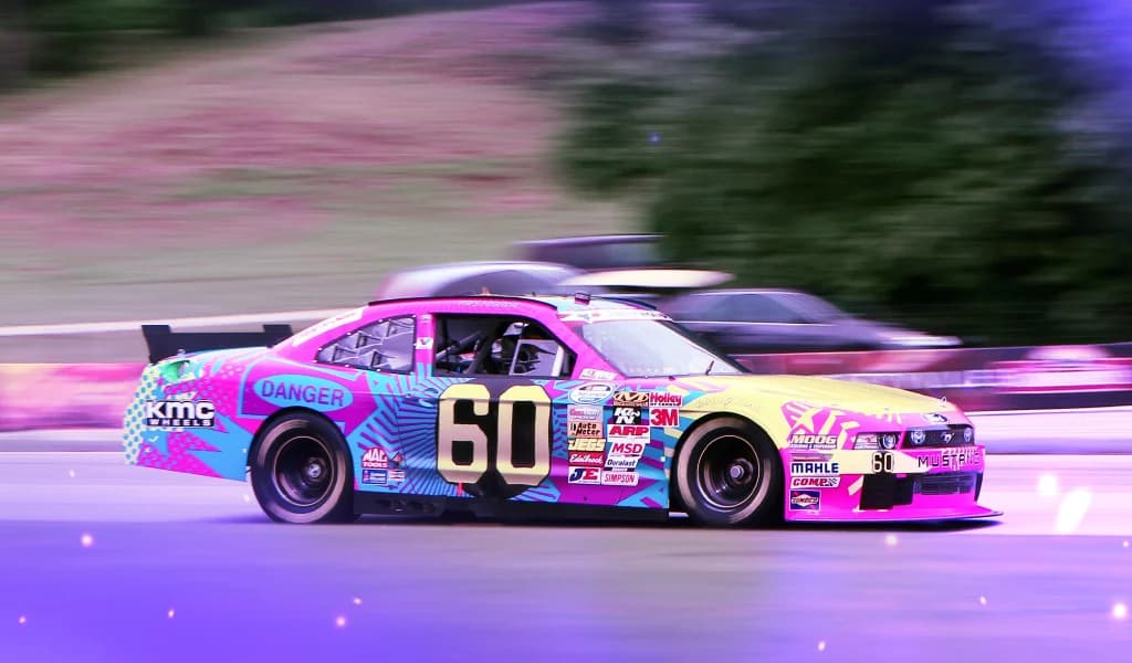Brightly painted race car with number 60 on the side speeding along a track, motion blur in the background.
