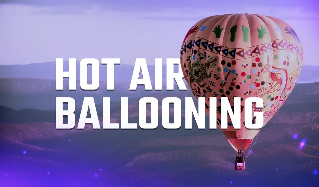 Colorful hot air balloon rising over rolling hills at sunrise.