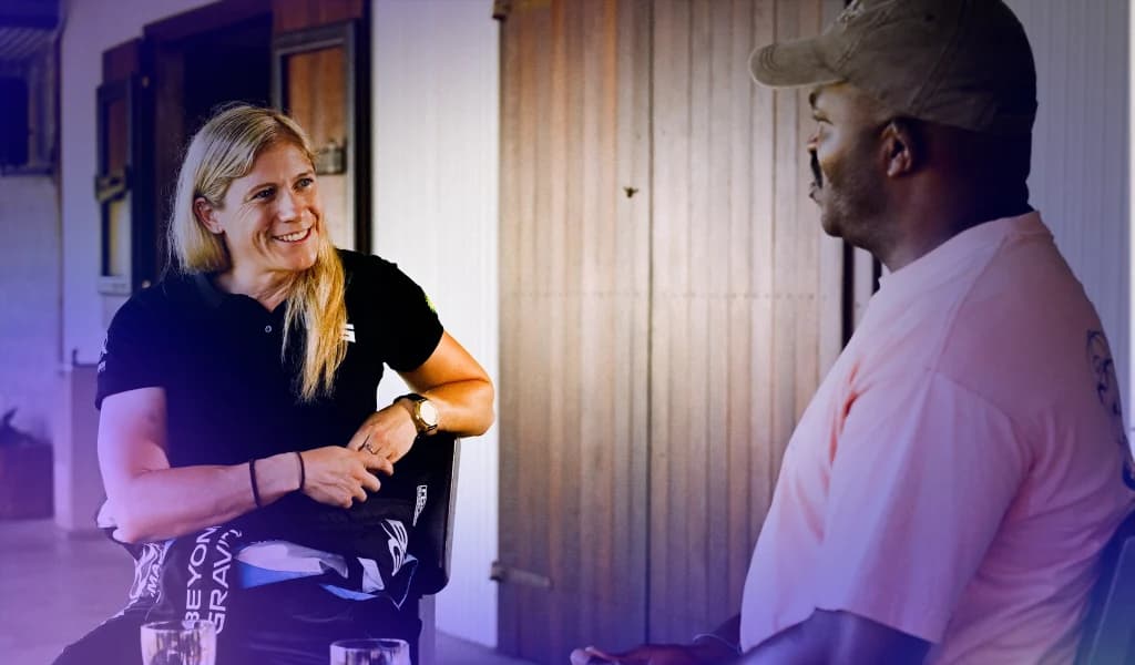 Two people, Emma McDonald and Selema Masekela, seated across from each other, engaged in a conversation in a relaxed setting.